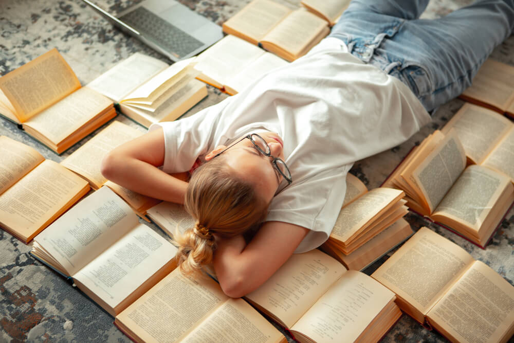 школьница лежит на книгах